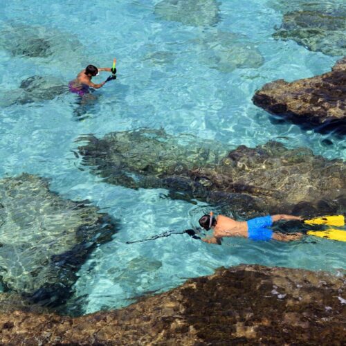 Es Migjorn Gran, Menorca / Spain - June 25, 2016: Clear water and snorkelers at Escorxada beach, Es Migjorn Gran, Menorca, Balearic Islands, Spain